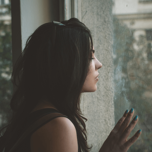 Femme de profil contre une vitre, regard vers l'extérieur
